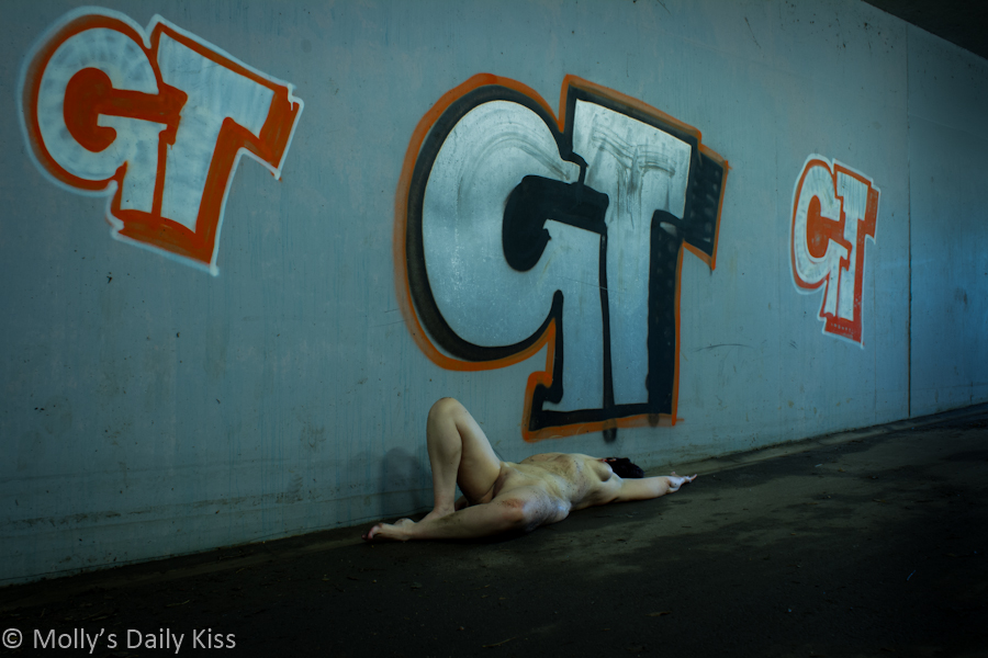 Laying naked infront of graffiti in subway
