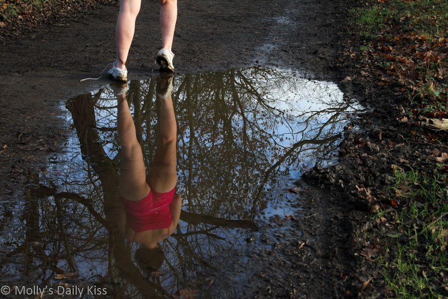 Refection of woman in pink lace panties in puddle