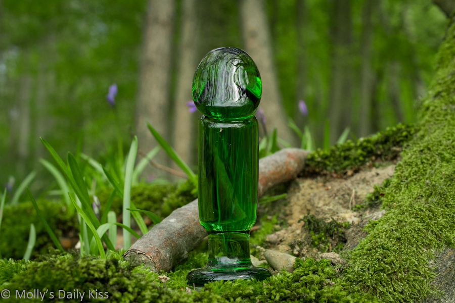 Green glass dildo out in the woods