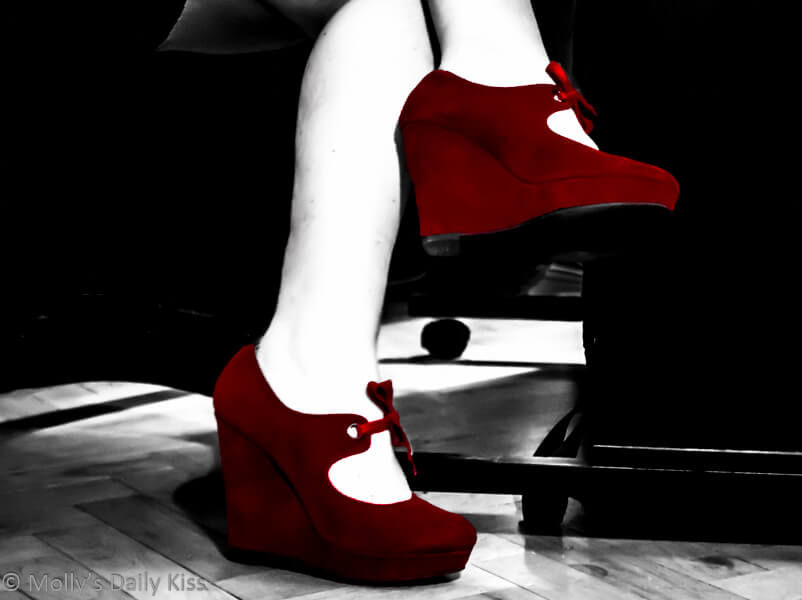 wearing red shoes sitting at desk. head over heels
