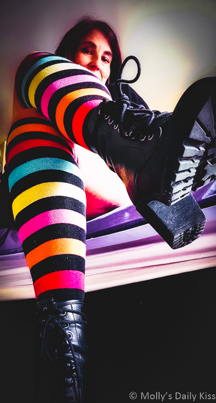 Molly looking down at camera in rainbow striped socks wearing high heel boots for post called Ask me
