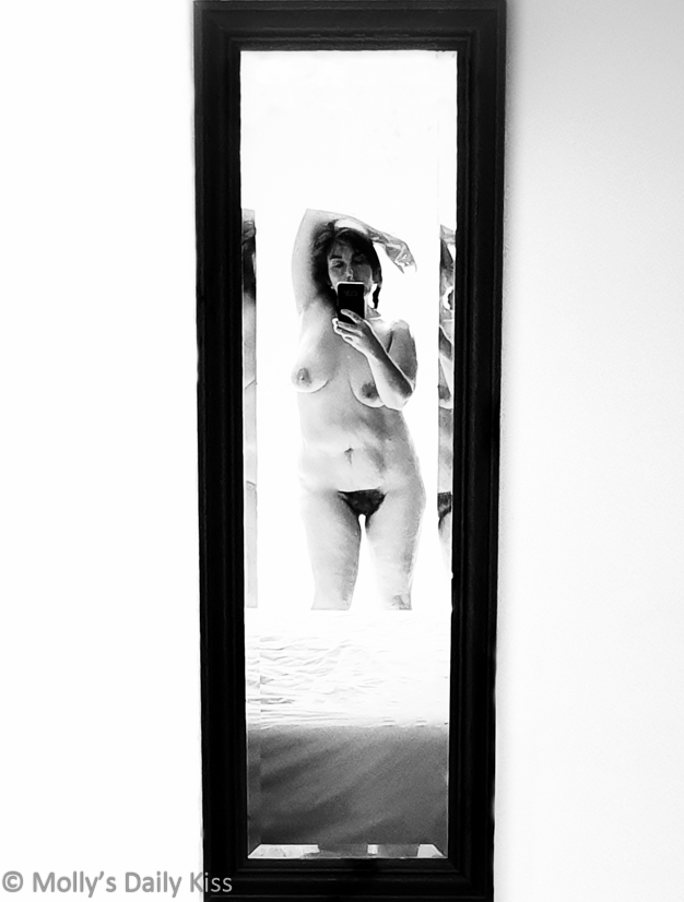 Black and white over exposed nude mirror self portrait of molly holding the camera