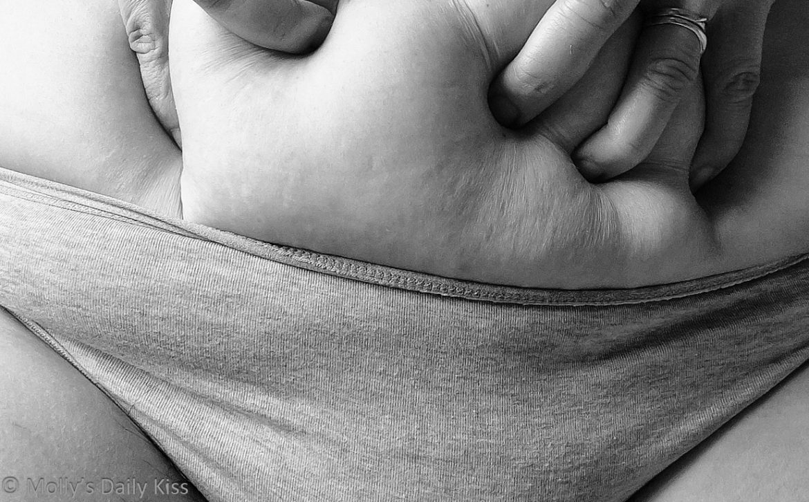 Cropped black and white image showing the top of mollys knickers and her fingers digging into her belly for post called soft spots