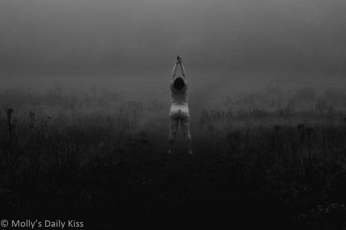 black and white of Molly standing naked in a field reaching up to the sky. The ground is dark but there is a frosty mist in the air for post called Peri-menopause nights