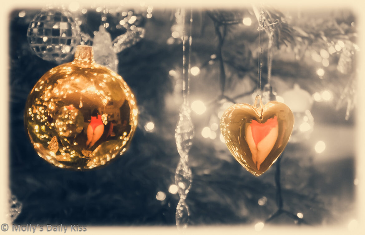 Golden baubles hanging on black and white tree with mollys bum reflected in them for post called glitter and glow